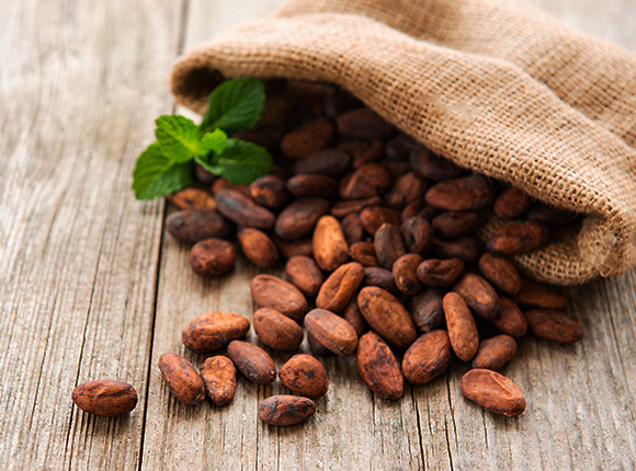 cocoa beans spilling out of a hessian bag on a wooden surface